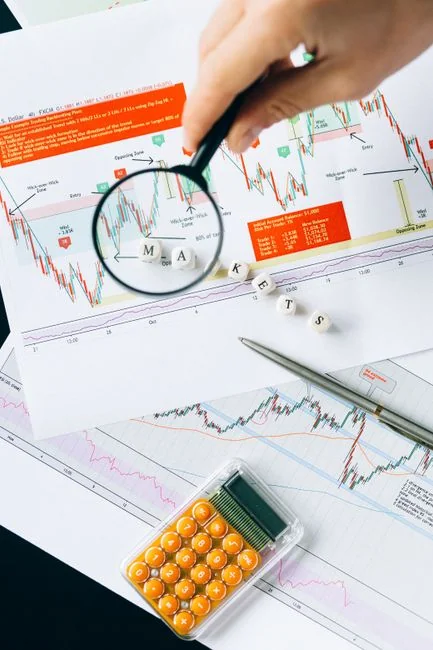 Mains en train de taper sur un ordinateur portable avec des graphiques de cryptomonnaies et l’écran d’un smartphone visibles, en se concentrant sur la finance numérique.